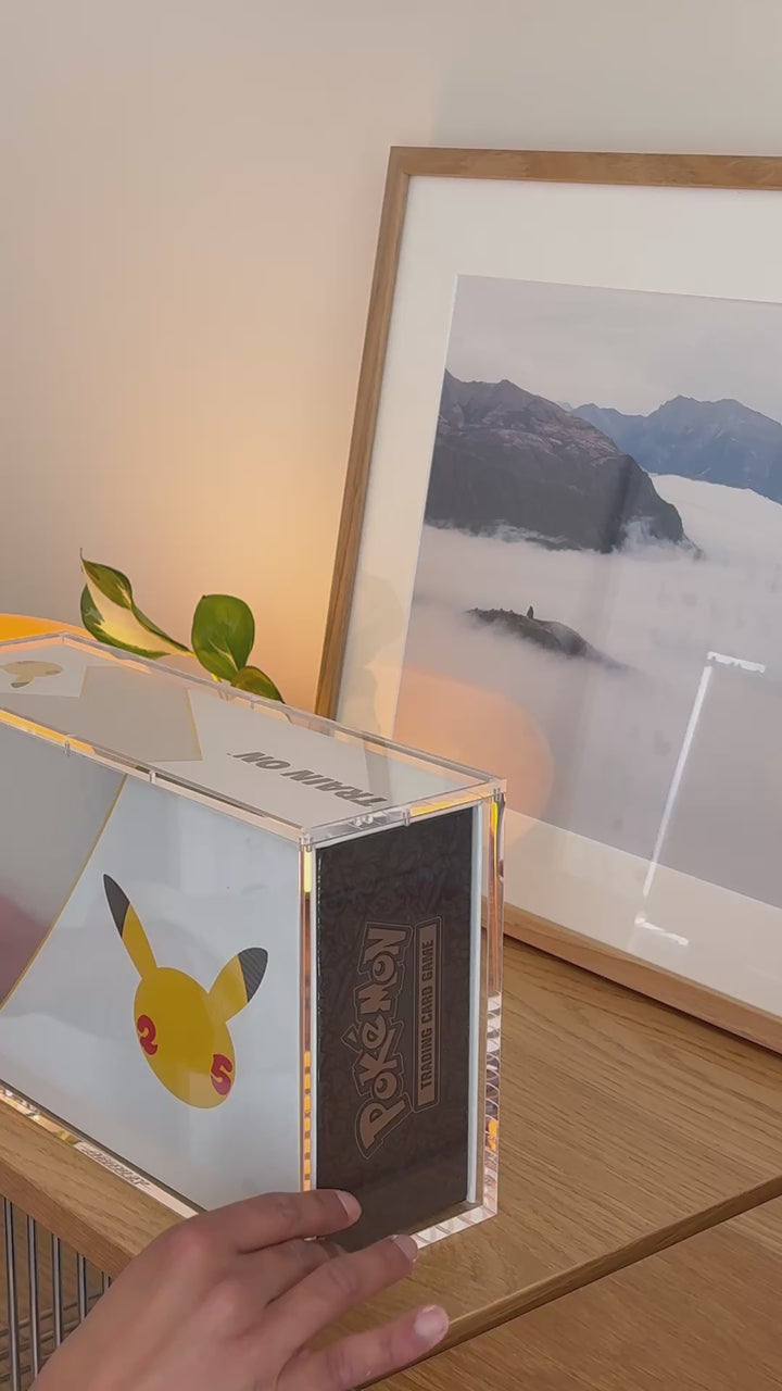 Pokémon 25th Anniversary Celebrations Ultra-Premium Collection acrylic case on a table – ACRYLIX
